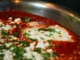 Shakshouka or eggs poached in a spicy tomato sauce with feta cheese and fresh herbs