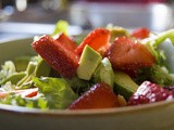 A photo of a strawberry and mixed greens salad with avocado, olive oil and balsamic vinegar dressing